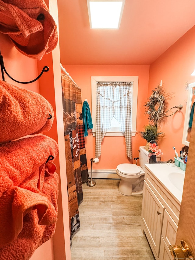 full bath with toilet, wood finished floors, curtained shower, vanity, and a baseboard heating unit