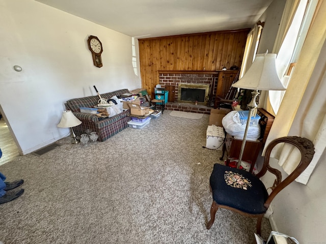 carpeted living area featuring wood walls and a brick fireplace