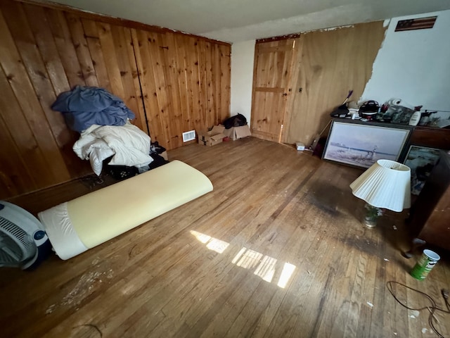 misc room featuring visible vents, wood-type flooring, and wood walls