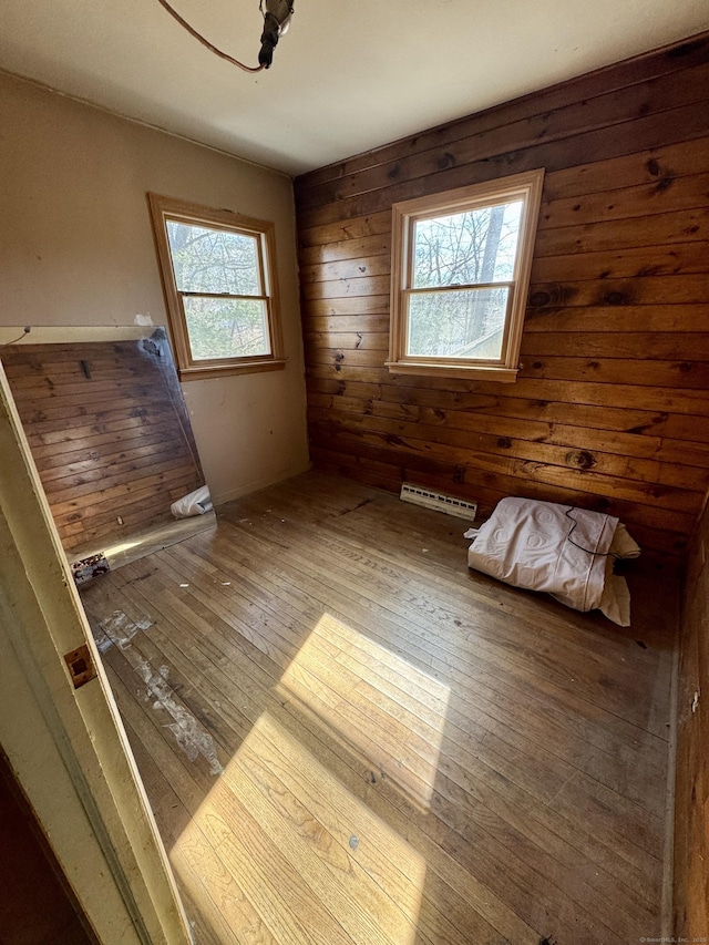 interior space featuring baseboard heating, wooden walls, and wood-type flooring