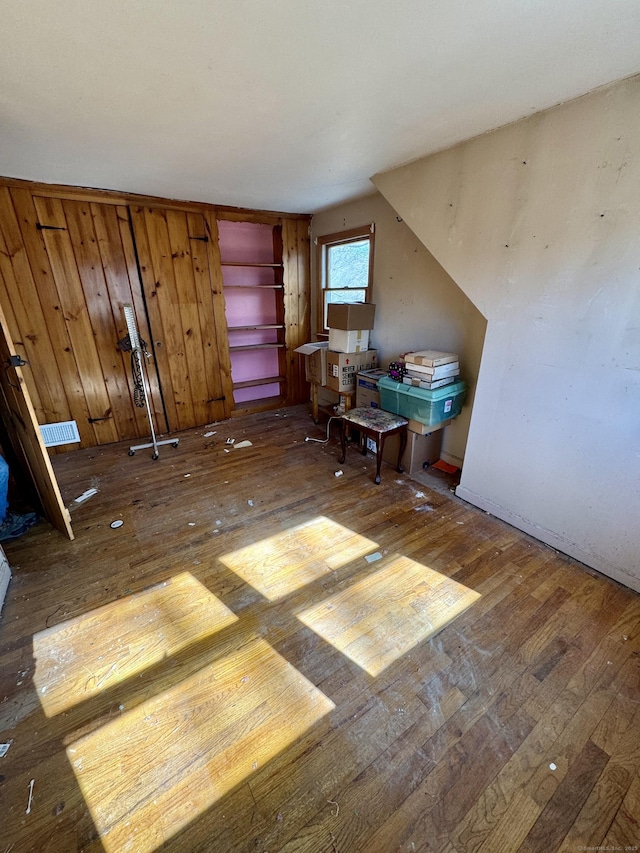 interior space featuring visible vents, wooden walls, and hardwood / wood-style flooring