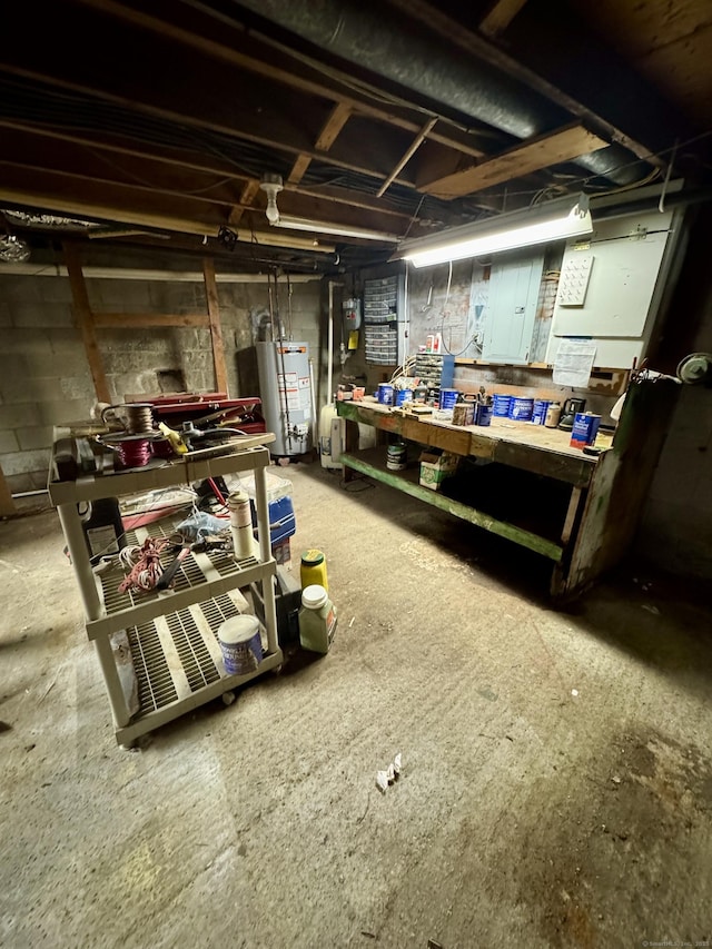 unfinished basement featuring gas water heater, a workshop area, and concrete block wall