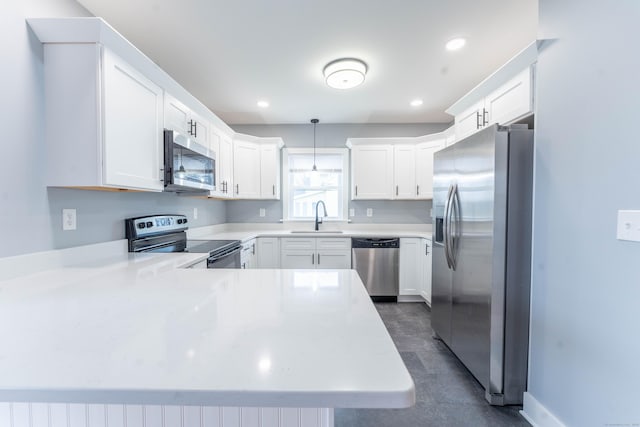 kitchen with a peninsula, appliances with stainless steel finishes, a sink, and light countertops