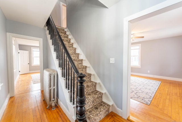 staircase with baseboards, hardwood / wood-style floors, a ceiling fan, and radiator