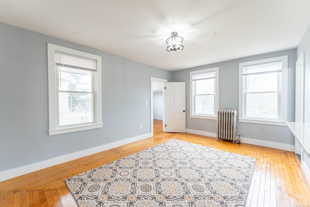 empty room with radiator, baseboards, and hardwood / wood-style floors