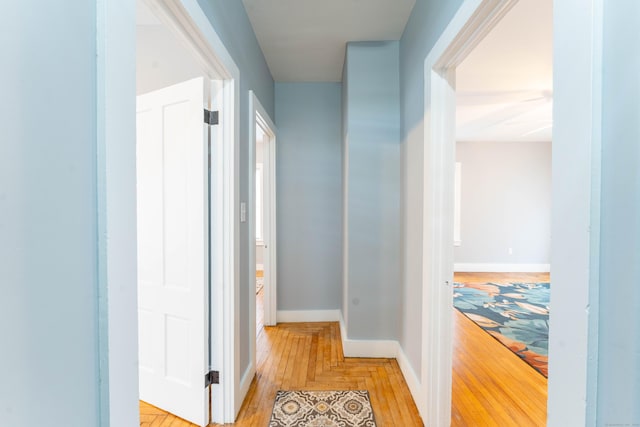 corridor with light wood-type flooring and baseboards