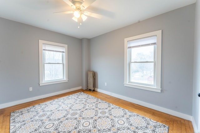 spare room with radiator heating unit, baseboards, and wood finished floors