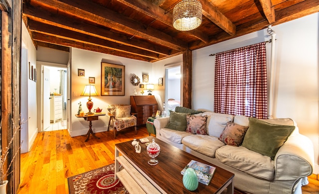 living room with beam ceiling, wood finished floors, baseboards, and wooden ceiling