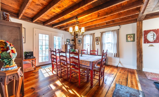 dining space featuring hardwood / wood-style floors, beamed ceiling, a healthy amount of sunlight, and a chandelier