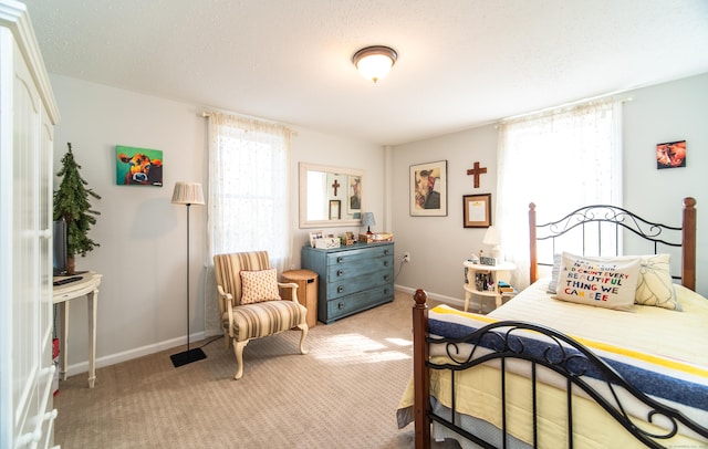 bedroom featuring light colored carpet, baseboards, and a textured ceiling