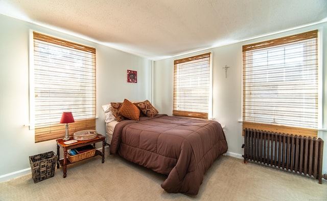 bedroom with carpet flooring, multiple windows, radiator heating unit, and a textured ceiling