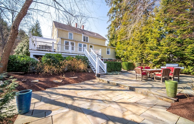 back of house featuring stairway, a patio, a wooden deck, and a chimney