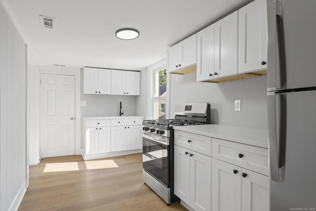 kitchen with visible vents, light wood-style flooring, stainless steel appliances, light countertops, and white cabinetry