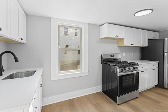 kitchen with light wood-type flooring, appliances with stainless steel finishes, light countertops, and a sink