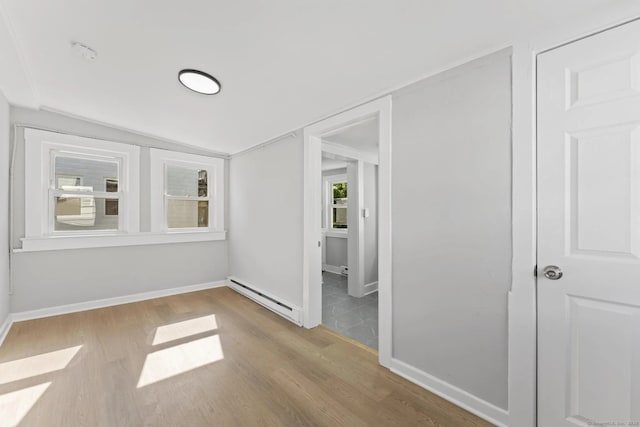 unfurnished room featuring a baseboard radiator, baseboards, and wood finished floors