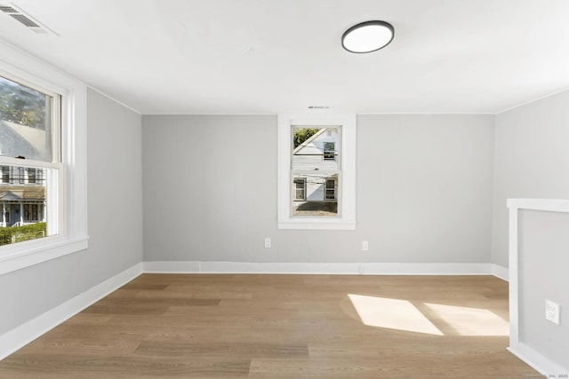 unfurnished room featuring light wood-type flooring, visible vents, and a wealth of natural light