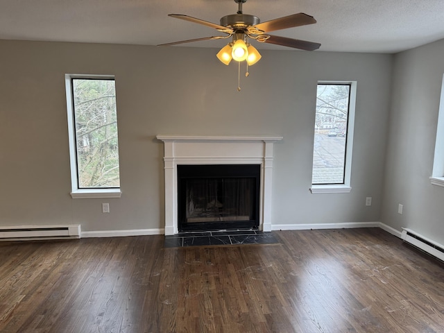 unfurnished living room with plenty of natural light, a fireplace with flush hearth, baseboard heating, and dark wood-type flooring