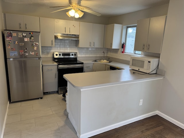 kitchen with a sink, stainless steel appliances, light countertops, under cabinet range hood, and backsplash