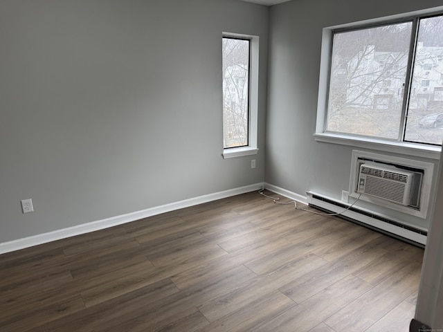 spare room featuring baseboards, a baseboard heating unit, dark wood-style flooring, and a wall mounted AC