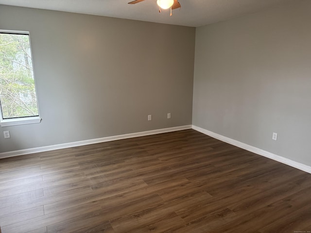 empty room featuring ceiling fan, dark wood finished floors, and baseboards