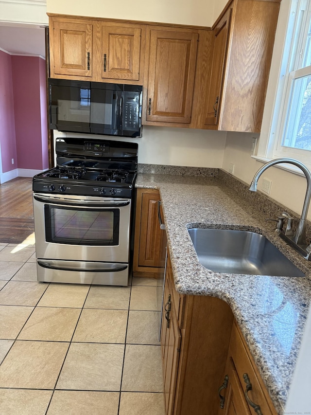 kitchen featuring gas range, black microwave, brown cabinets, and a sink