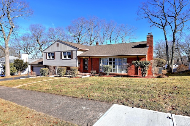 tri-level home with a front lawn, brick siding, driveway, and a chimney