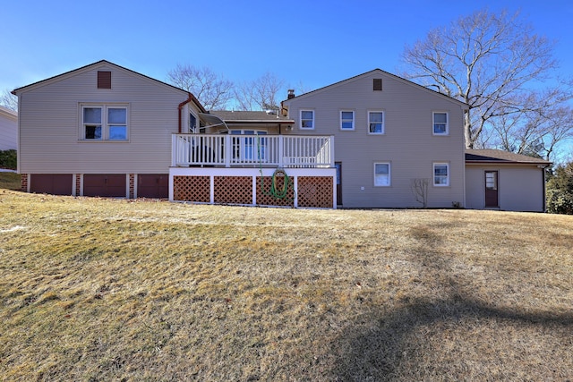 back of house featuring a lawn, a deck, and an attached garage