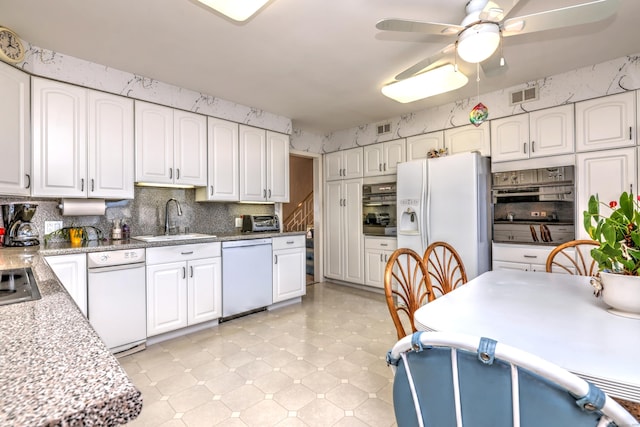 kitchen with wallpapered walls, white appliances, visible vents, and a sink