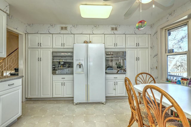 kitchen featuring visible vents, stainless steel oven, wallpapered walls, and white fridge with ice dispenser