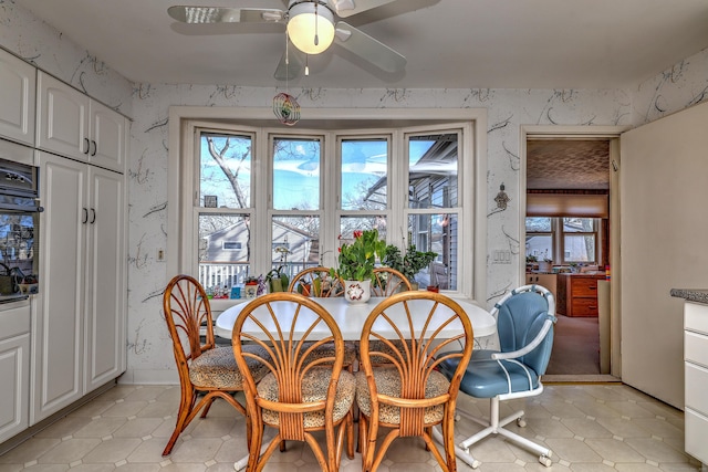 dining space featuring wallpapered walls and ceiling fan