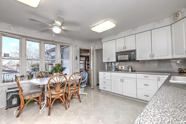 kitchen with a sink, black appliances, a ceiling fan, and white cabinetry