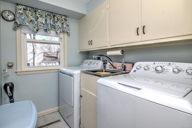 clothes washing area featuring visible vents, washer and dryer, cabinet space, light tile patterned floors, and baseboards