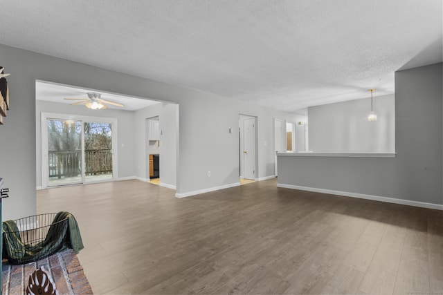 unfurnished living room with ceiling fan, a textured ceiling, baseboards, and wood finished floors