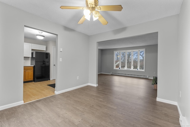 unfurnished living room featuring baseboards, light wood-style flooring, baseboard heating, and a textured ceiling