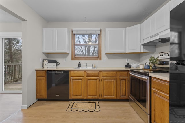 kitchen featuring under cabinet range hood, light countertops, light wood-type flooring, black appliances, and a sink