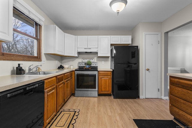 kitchen featuring under cabinet range hood, light countertops, light wood-type flooring, black appliances, and white cabinetry