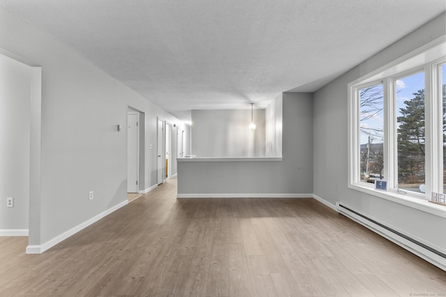 empty room with a baseboard radiator, a textured ceiling, baseboards, and wood finished floors