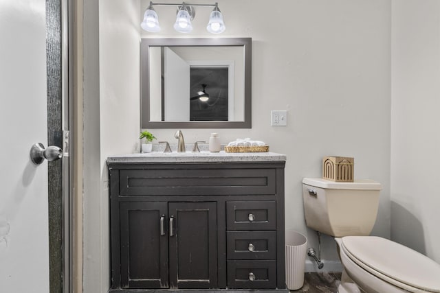 half bath featuring vanity, toilet, and baseboards