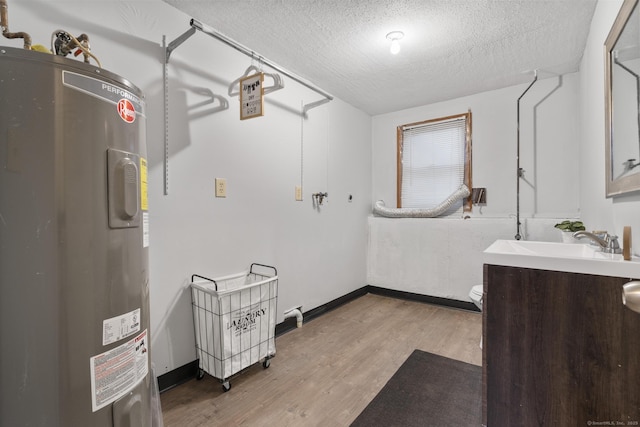 interior space featuring electric water heater, a textured ceiling, vanity, wood finished floors, and baseboards