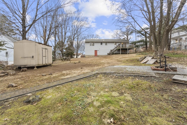 view of yard featuring a storage shed, a deck, an outdoor structure, and stairs