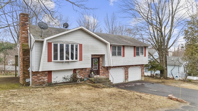 raised ranch with driveway, brick siding, a chimney, and an attached garage