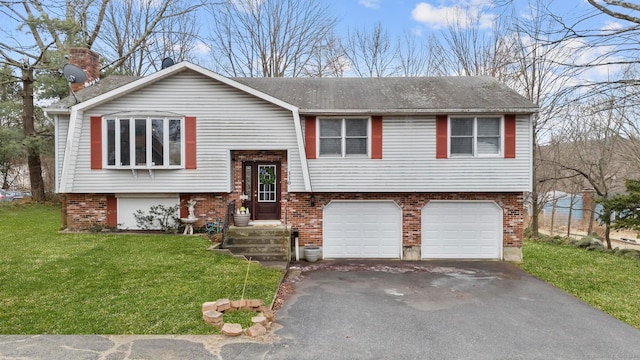 split foyer home featuring aphalt driveway, a garage, brick siding, a chimney, and a front yard