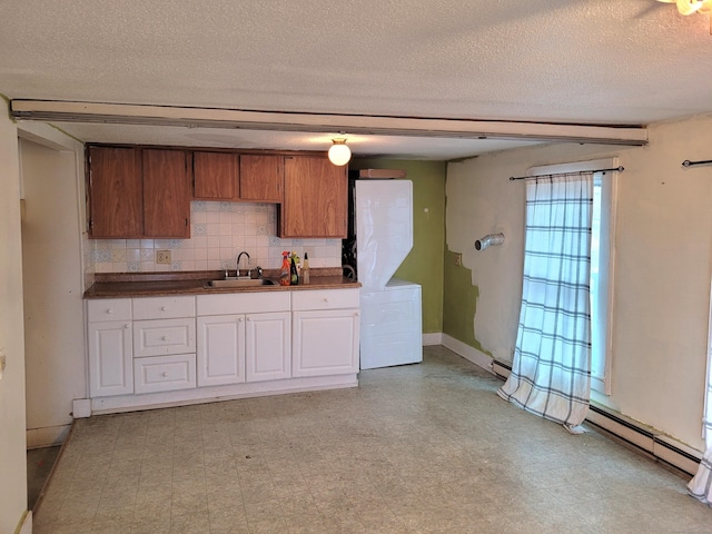 kitchen featuring a sink, decorative backsplash, light floors, washer / clothes dryer, and dark countertops