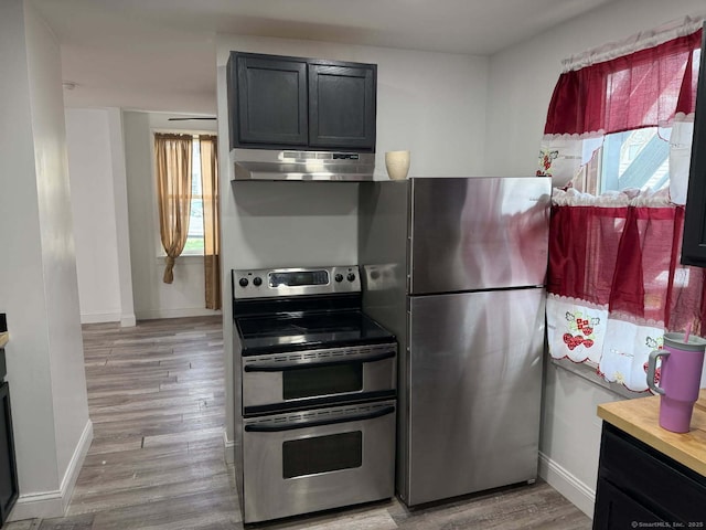kitchen featuring under cabinet range hood, appliances with stainless steel finishes, plenty of natural light, and baseboards