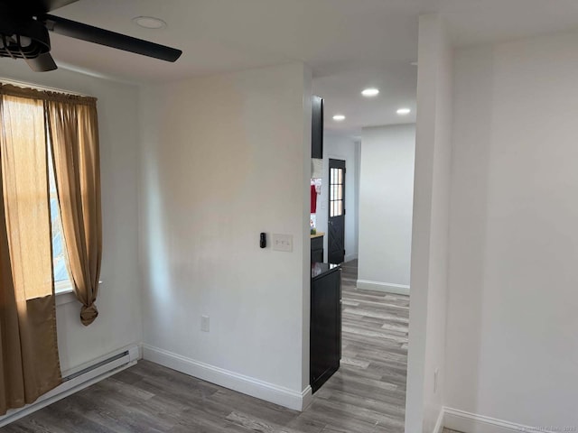 empty room featuring wood finished floors, recessed lighting, ceiling fan, baseboard heating, and baseboards