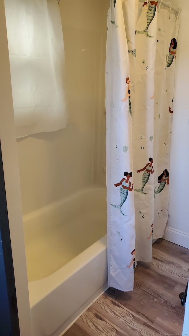 bathroom featuring baseboards, shower / bath combo, and wood finished floors