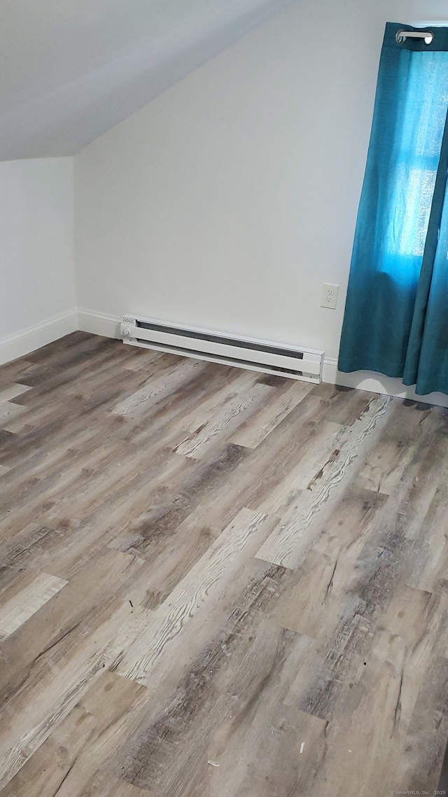 additional living space featuring baseboards, baseboard heating, and wood finished floors