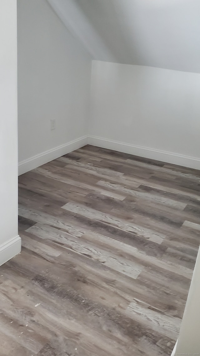 additional living space featuring baseboards, lofted ceiling, and wood finished floors