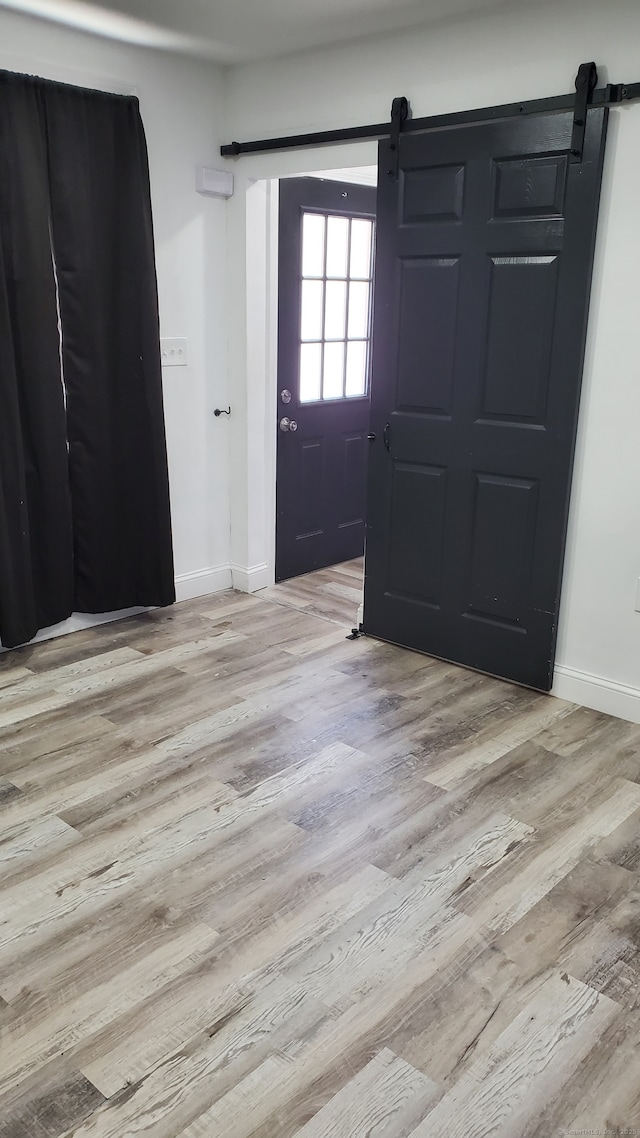 entrance foyer featuring baseboards, a barn door, and wood finished floors