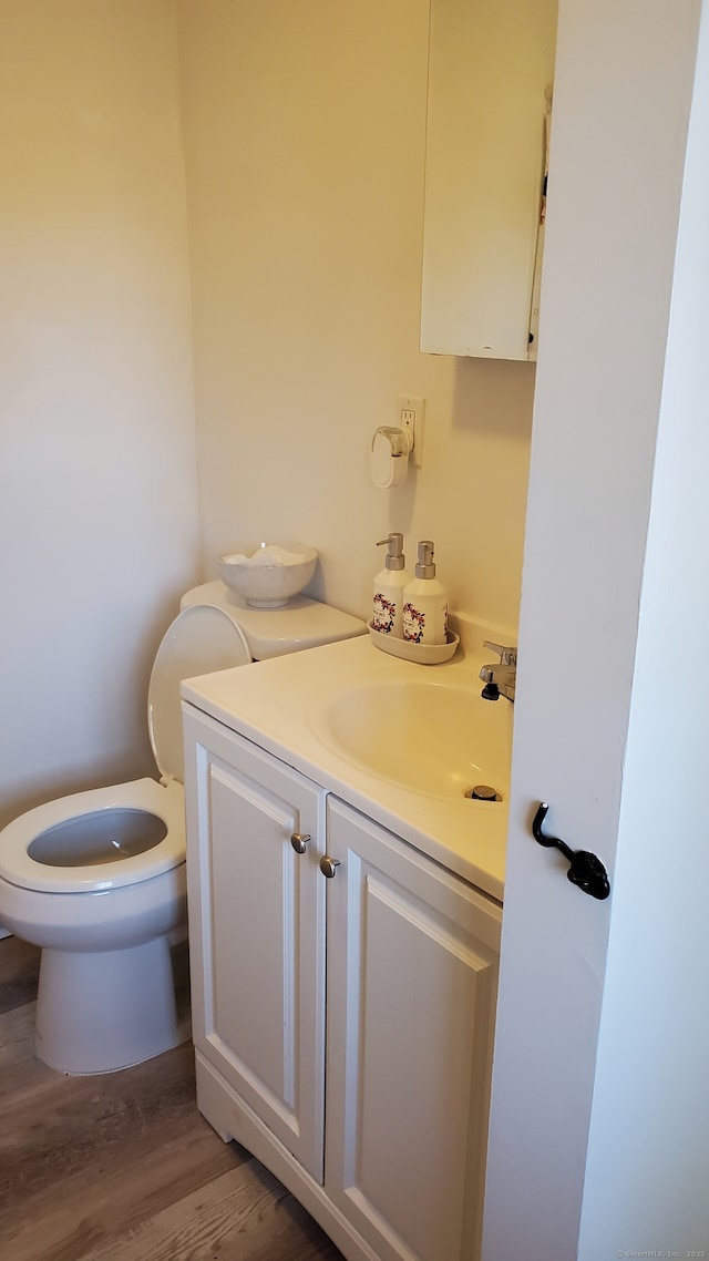 half bathroom featuring vanity, toilet, and wood finished floors
